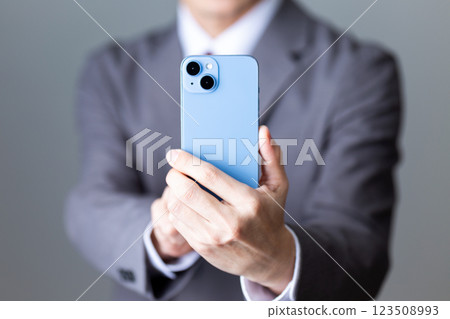一位身穿灰色西裝的中年男性商人用智慧型手機拍照 123508993