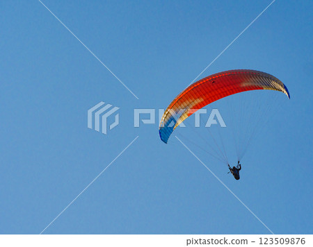 Paraglider flying in blue sky. Paraglider flying in blue sky. 123509876