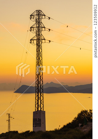 High voltage towers on coast at sunset High voltage towers on coast at sunset 123509912