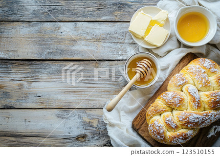 loave of homemade Challah bread with honey and butter on white wooden table.Top view. Copy space 123510155