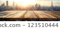 Wooden Table Surface with Sunset Blurry Cityscape and Nature Background, Warm Tones, and Soft Focus Lights Creating a Cozy Atmosphere for Relaxation 123510444