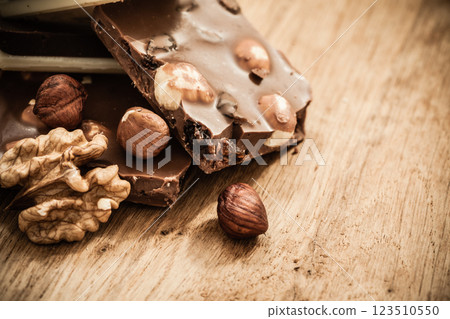 Milk chocolate and hazelnuts on wooden table Milk chocolate and hazelnuts on wooden table 123510550
