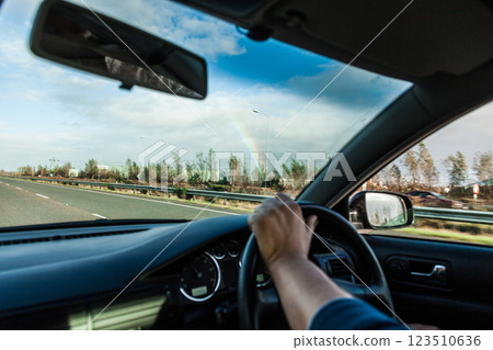 Male driver hands on steering wheel of a car and road 123510636