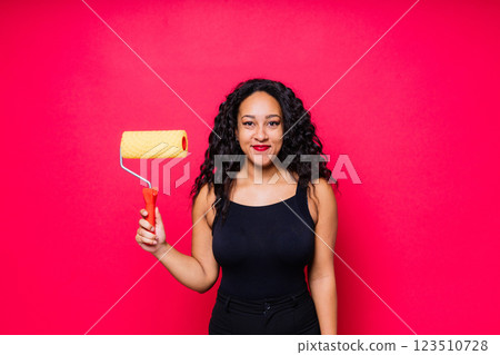 Happy young African woman with paintroller, toothy smile during home renovation 123510728