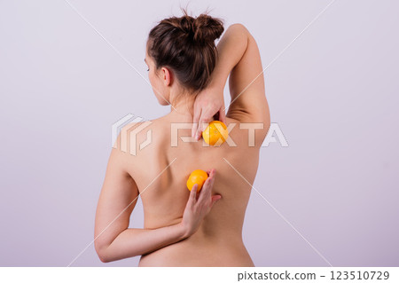 Slender athletic woman topless holds a tangerine in her hands. Cellulite. Healthy lifestyle Slender athletic woman topless holds a tangerine in her hands. Cellulite. Healthy lifestyle 123510729