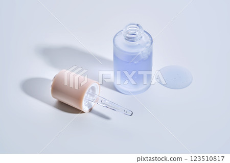 Cosmetic bottle, dropper and a drop of serum on a white background. 123510817