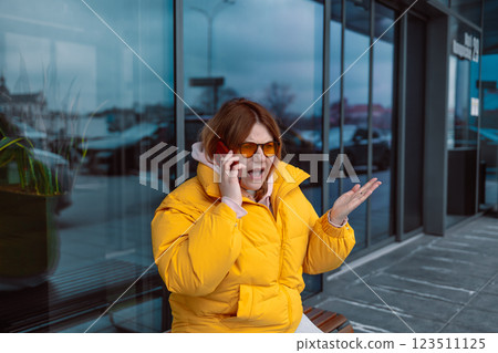 Negative emotions. Angry young woman wearing a yellow jacket and sunglasses talking over phone disappointed hear bad news, sad pensive girl speaking having unpleasant smartphone conversation and Negative emotions. Angry young woman wearing a yellow jacket and sunglasses talking over phone disappointed hear bad news, sad pensive girl speaking having unpleasant smartphone conversation and 123511125