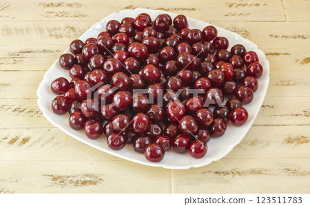 The fruits of ripe red cherry berries on a white square plate 123511783