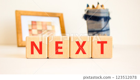 Next symbol. Concept word Next on beautiful wooden blocks. Beautiful picture frame and colored pencils. Beautiful white table white background. Business, lifestyle, support next concept. Copy space. Next symbol. Concept word Next on beautiful wooden blocks. Beautiful picture frame and colored pencils. Beautiful white table white background. Business, lifestyle, support next concept. Copy space. 123512078
