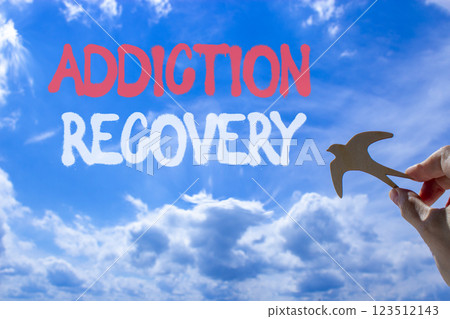 Addiction recovery symbol. Concept words Addiction recovery on beautiful blue sky. Psychologist hand, wooden bird. Beautiful blue sky cloud background. Psychology addiction recovery concept Copy space 123512143