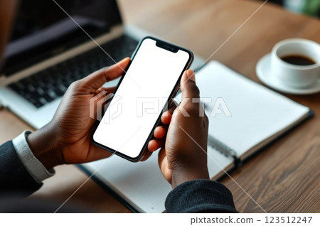 Person Using AI Assistant on Smartphone While Taking Notes at a Workspace 123512247