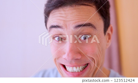 Man making funny face with wide eyes and smiling 123512424