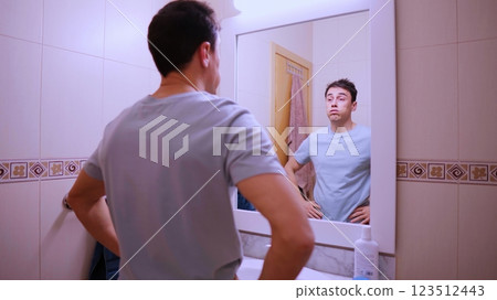 Sleepy man looking at mirror in bathroom before work Sleepy man looking at mirror in bathroom before work 123512443