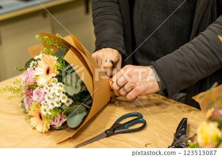 Florist arranging flowers in bouquet for delivery or client pickup Florist arranging flowers in bouquet for delivery or client pickup 123513087