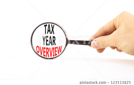 Tax year overview symbol. Concept words Tax year overview on beautiful black magnifying glass. Beautiful white background. Businessman hand. Business tax year overview concept. Copy space. 123513825