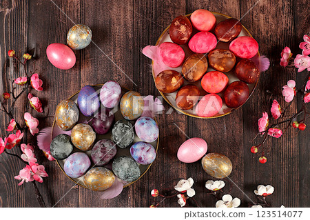 Easter celebration concept, marble Easter eggs painted with onion peel, hibiscus tea and pink matcha on a wooden background with sakura branches, ideas for homemade Easter cooking Easter celebration concept, marble Easter eggs painted with onion peel, hibiscus tea and pink matcha on a wooden background with sakura branches, ideas for homemade Easter cooking 123514077