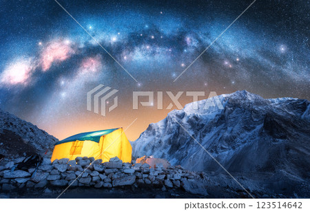 Milky Way, glowing yellow tent in snowy mountains at starry night 123514642