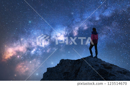 Glowing Milky Way and woman on mountain peak at starry night Glowing Milky Way and woman on mountain peak at starry night 123514670