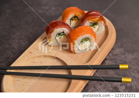 Set of sushi roll with rice and fish and chopsticks on wooden serving board. Dark black texture background with copy space. Close up. Japan menu. Asian food 123515231