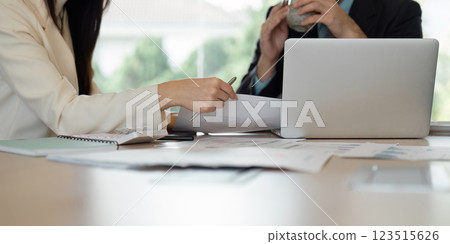 Business professionals collaborating in a modern office, analyzing financial reports and discussing strategies. 123515626