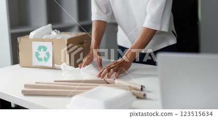 Person sorting recyclable materials on a table, organizing waste in a modern workspace. 123515634