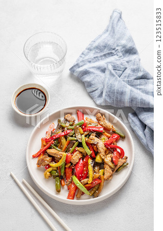 Stir-fry with vegetables and meat on wooden board on white background 123515833