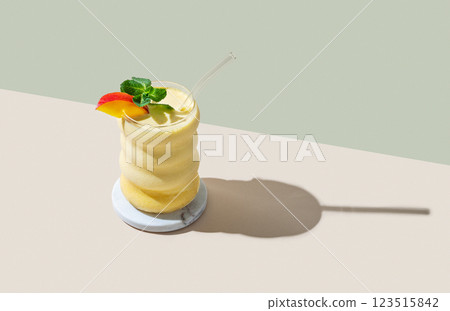 Vegetarian smoothie with mango and banana in a glass on a green and yellow background with shadow. Vegetarian smoothie with mango and banana in a glass on a green and yellow background with shadow. 123515842