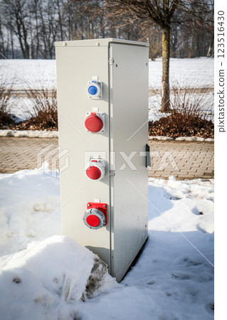 Outdoor Electrical Power Distribution Box with Industrial Plugs in a Snowy Landscape Outdoor Electrical Power Distribution Box with Industrial Plugs in a Snowy Landscape 123516430