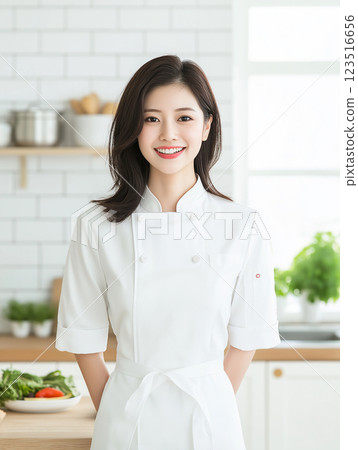 Chef in a kitchen cooking with a smile, featuring vegetables and culinary skills in a white apron 123516656