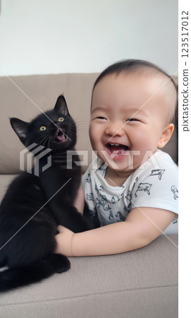 Black kitten and smiling baby sharing joyful moments on a couch, having fun and being cute 123517012