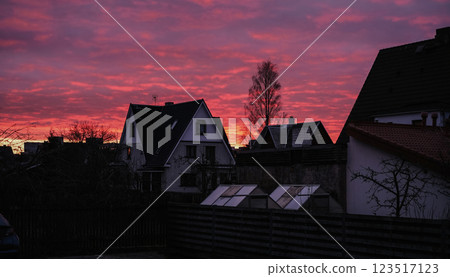 A white houses with a red sunset is in front. The house is surrounded by trees 123517123