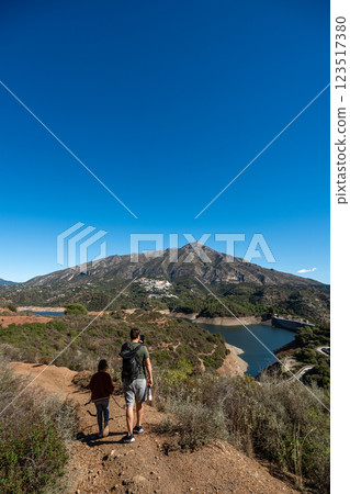 Father and daughter hiking on mountain trail near scenic lake under clear blue sky, La Concepcion Father and daughter hiking on mountain trail near scenic lake under clear blue sky, La Concepcion 123517380