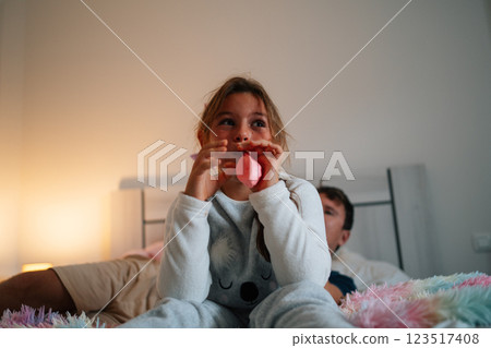 Young caucasian child playing on bed with adult male in background 123517408