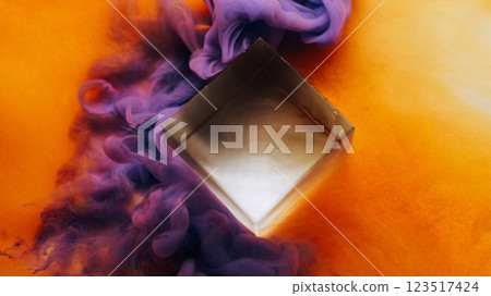 Mist blow. Magic cloud. Color smoke wave spill near glass cube diamond. Violet vapor paint haze flow on vivid blur orange background. 123517424