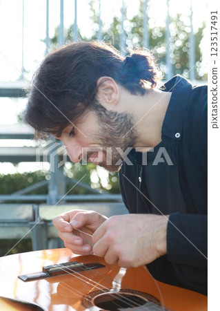 Man's Hand Passes Guitar Strings Preparatively 123517491