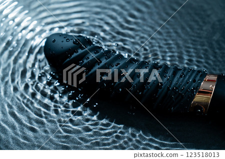 Black silicone vibrator in water. Circles on water around sex toy. Black silicone vibrator in water. Circles on water around sex toy. 123518013