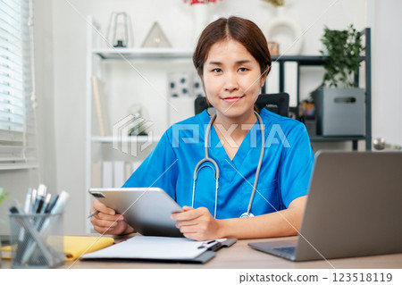 A healthcare professional in blue scrubs using a tablet in a modern office setting, showcasing technology in healthcare. A healthcare professional in blue scrubs using a tablet in a modern office setting, showcasing technology in healthcare. 123518119