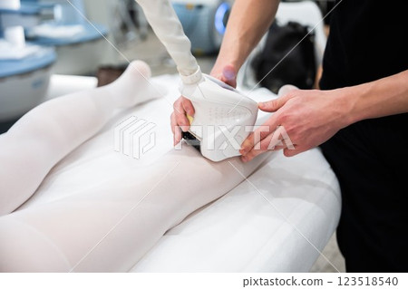 Skin treatment session using device on clients leg in spa setting Skin treatment session using device on clients leg in spa setting 123518540