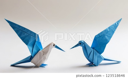 Intricate origami blue birds engaged in a stylized pose, perfect for art enthusiasts, creative projects, and decorative elements in personal or educational settings. 123518646