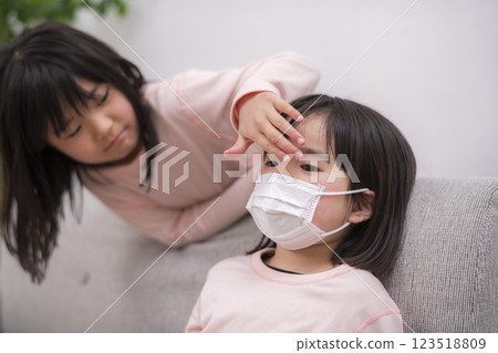 An older sister worries about her younger sister who has a fever 123518809