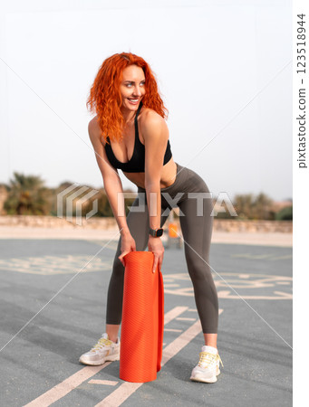 Sensuous jogger woman holding rolled up exercise Sensuous jogger woman holding rolled up exercise 123518944