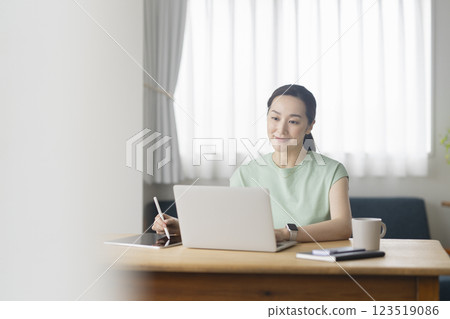 Woman in her 30s working on a laptop, working from home, image 123519086