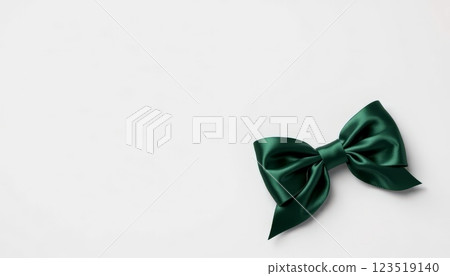 A luxurious green satin bow laid flat against a neutral background, symbolizing elegance, perfect for gift wrapping and special occasions. 123519140