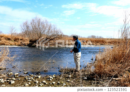 一位經驗豐富的漁夫沿著寬闊的河床向水流走去 123521591