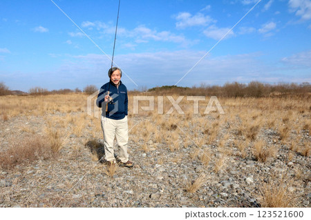 A veteran fisherman walking along the wide riverbed toward the current A veteran fisherman walking along the wide riverbed toward the current 123521600