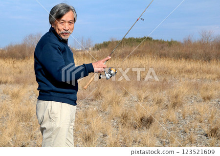 A veteran fisherman walking along the wide riverbed toward the current A veteran fisherman walking along the wide riverbed toward the current 123521609