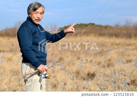 A veteran fisherman walking along the wide riverbed toward the current A veteran fisherman walking along the wide riverbed toward the current 123521610