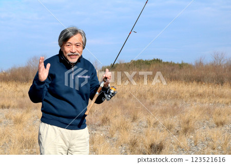A veteran fisherman walking along the wide riverbed toward the current A veteran fisherman walking along the wide riverbed toward the current 123521616