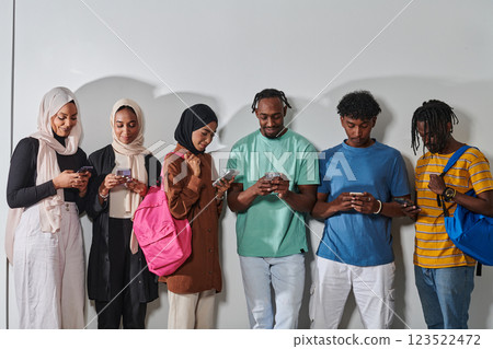 A diverse group of students, immersed in the digital age, stands united while engaging with their smartphones against a white backdrop, symbolizing the modern era of connectivity, communication, and A diverse group of students, immersed in the digital age, stands united while engaging with their smartphones against a white backdrop, symbolizing the modern era of connectivity, communication, and 123522472