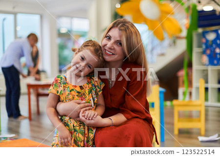 A cute little girl kissing and hugs her mother in preschool 123522514